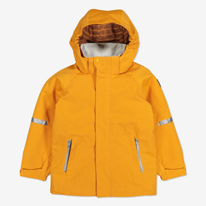 Kids waterproof jacket in yellow, comes with a detachable hood, adjustable cuffs and reflectors, made of soft shell fabric.