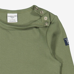 Close up view of kids green top with helpful poppers on one shoulder for easy dressing. Made in soft organic cotton