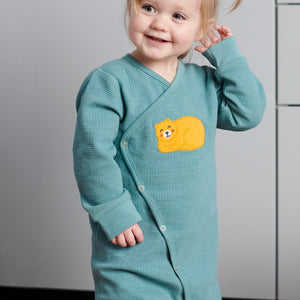 Toddler wearing wraparound onesie for newborn babies in GOTS organic cotton with adorable sleeping bear applique. With full length popper fastenings for speedy changes. Quality ribbed trim for added comfort.