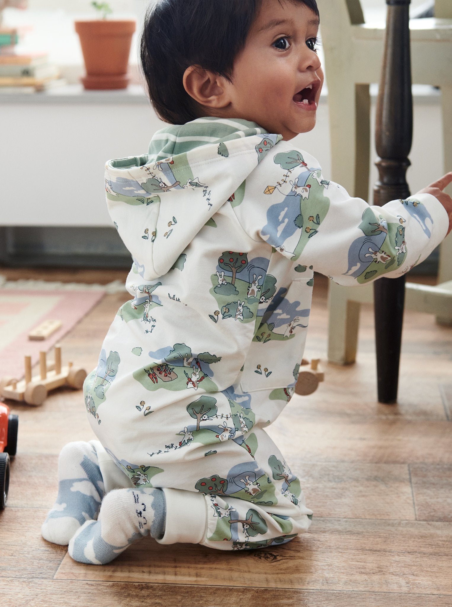 A toddler wearing a bunny print all-in-one in GOTS organic cotton, paired with plain matching cotton socks