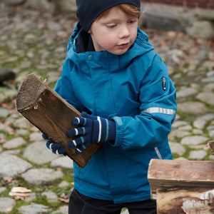 Boy playing outside wearing 100% waterproof kids coat in bright blue and 100% waterproof trousers in black. Accessories with warm merino wool beanie hat in navy