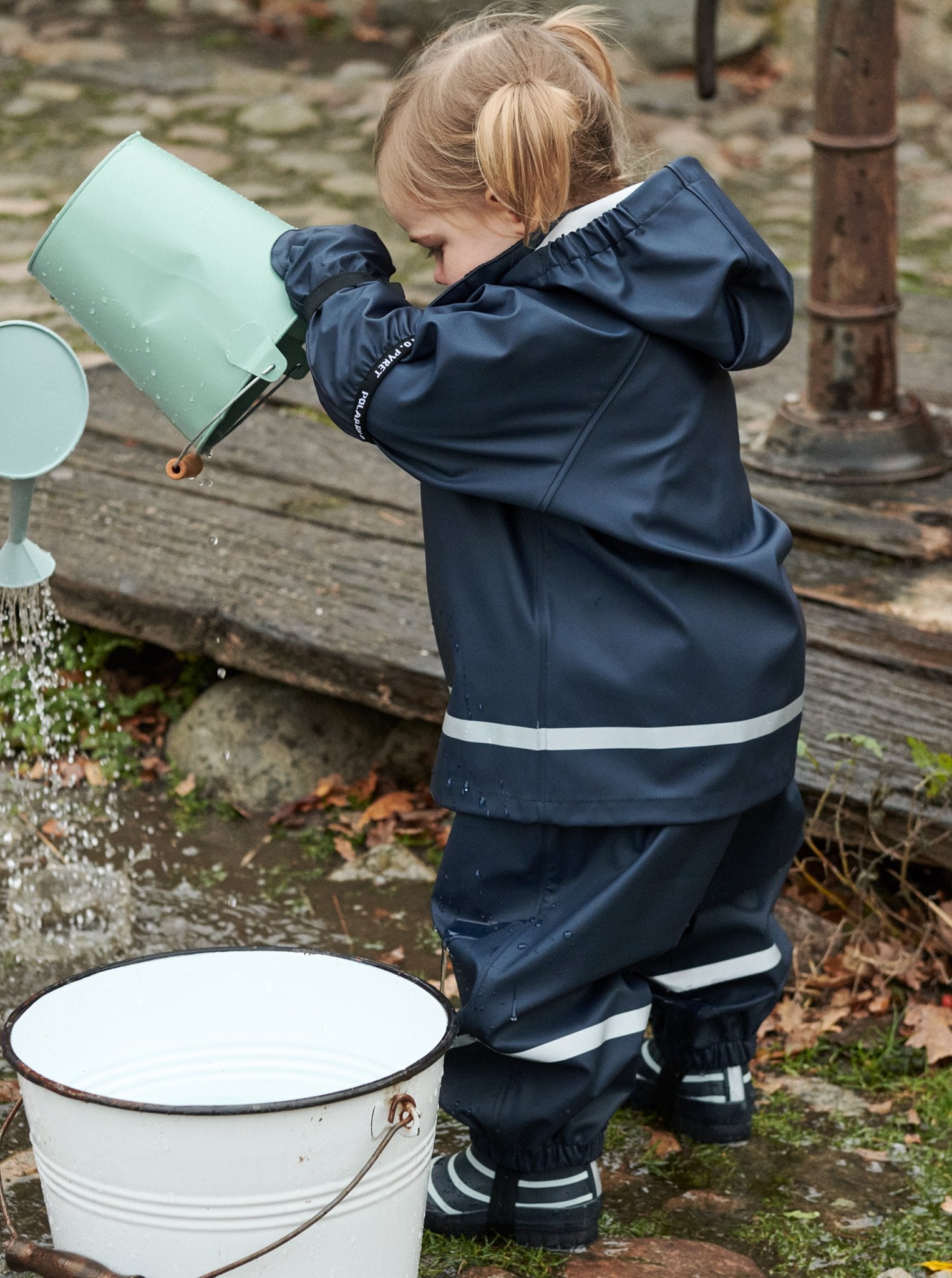 Kid playing in the puddle wearing a navy raincoat and kids wellies. Ethically made sturdy sole and has M3 reflective strips.