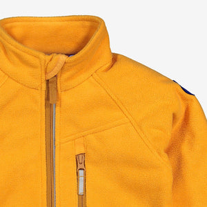 Close up shot of a kids waterproof fleece jacket in yellow, with reflector zips, made of soft and breathable fabric.