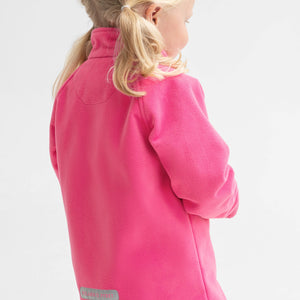 Side view of a young girl wearing a pink, kids waterproof fleece jacket, with cuff thumbholes, made of soft fabric.