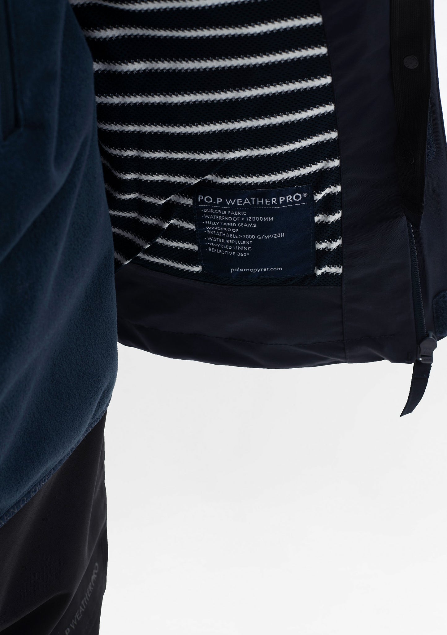 Close up shot of the clothing label of kids waterproof jacket in navy by Polarn O. Pyret, made of lightweight shell fabric.