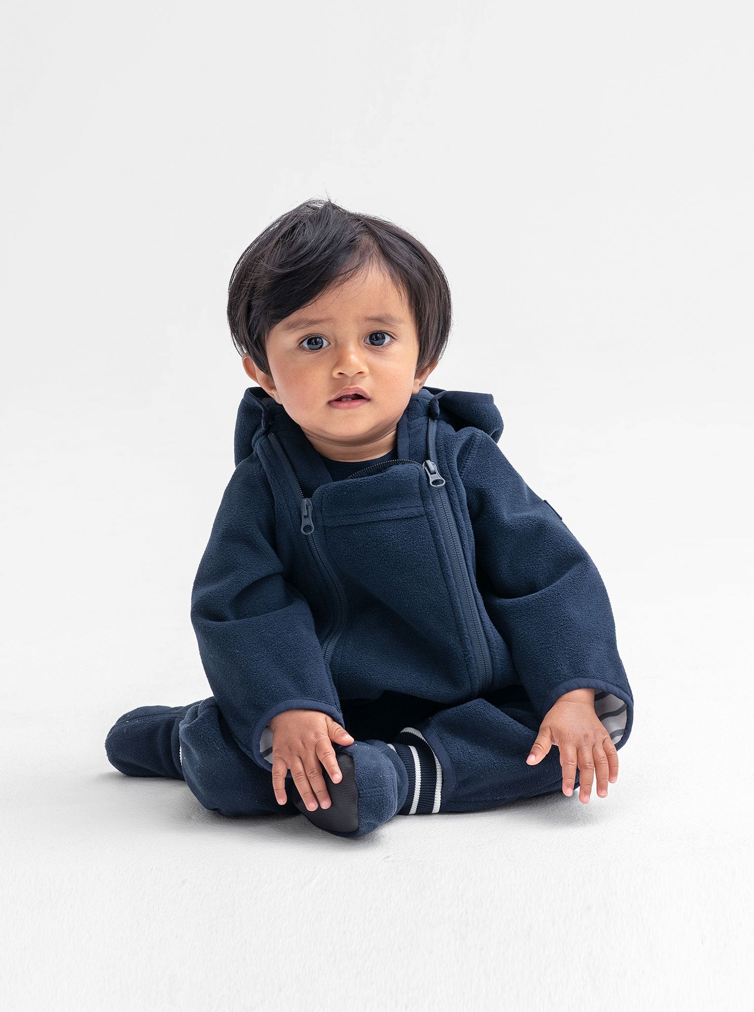 Baby boy wearing a navy windproof fleece baby pramsuit with integrated feet