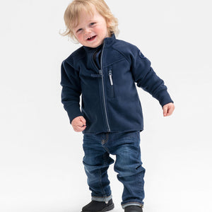 A toddler wearing a navy, waterproof kids fleece jacket, made of warm & comfortable fabric material, paired with blue jeans.