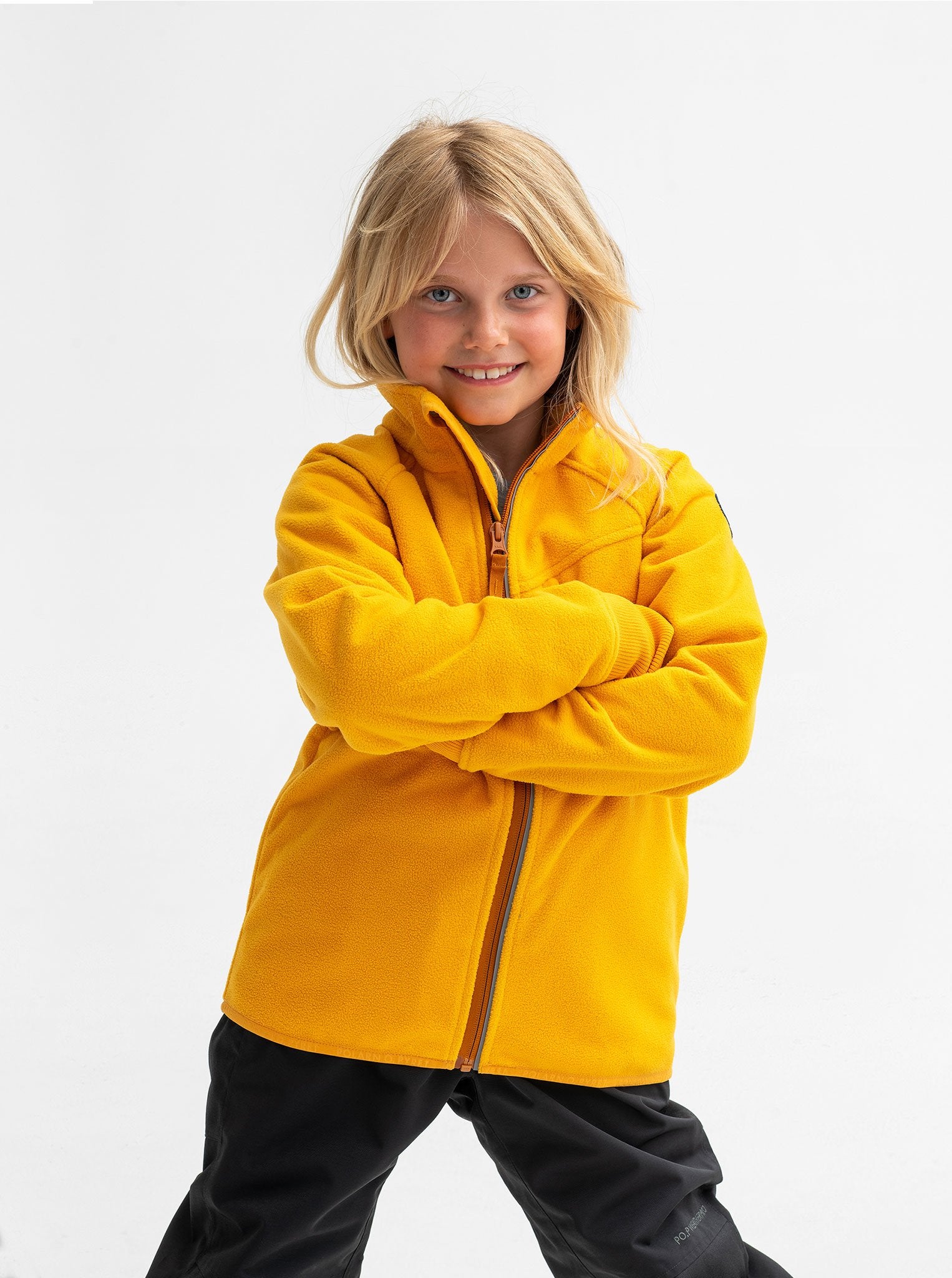 A young girl sporting a yellow, kids waterproof fleece jacket, with zip reflectors and cuff thumbholes, made of soft fabric.