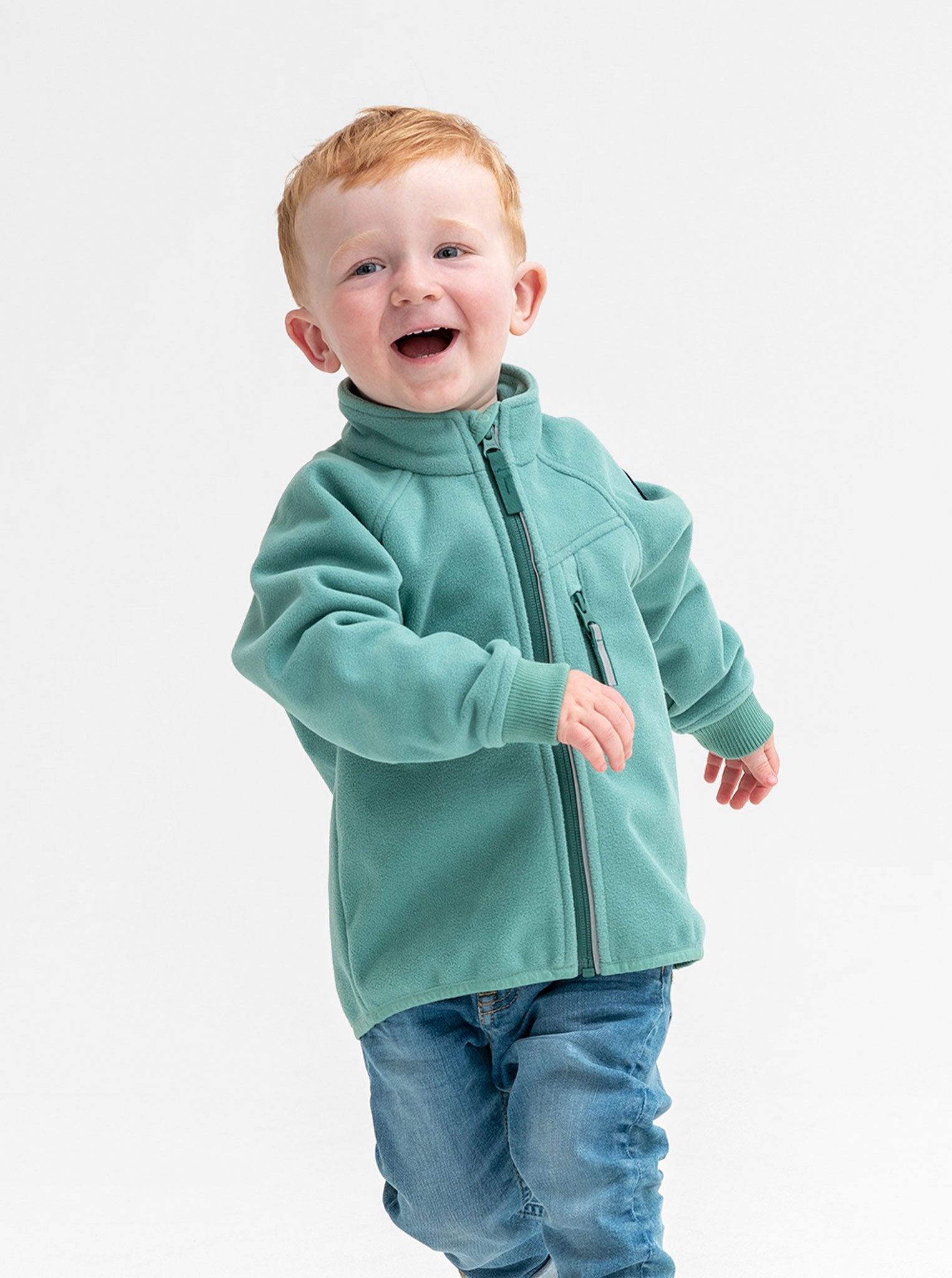 A young boy wearing a green, kids waterproof fleece jacket, with reflector zips and fit cuffs, made of breathable fabric.