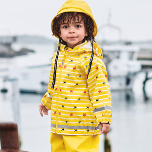 A little boy sporting a yellow raincoat for kids with frog & stripes pattern, paired with kids rain trousers and bucket hat. 